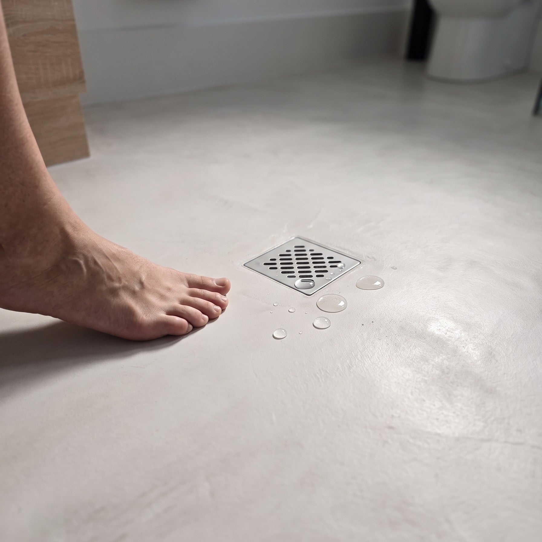Low angle view of a smooth matt microcement bathroom floor leading to a freestanding bath